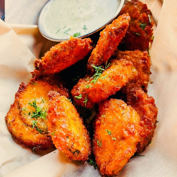 Crispy vegan fried chicken pieces with fresh herbs and a side of creamy dipping sauce.